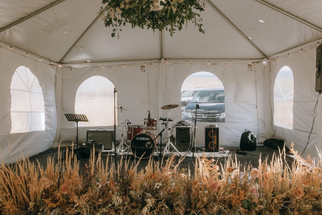 Wedding tent reception setup with place cards and burgundy floral centerpieces