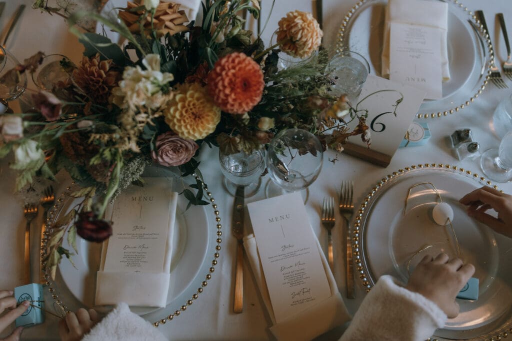 Fall wedding reception tablescape with burgundy florals and place settings at Wolf Creek Ranch
