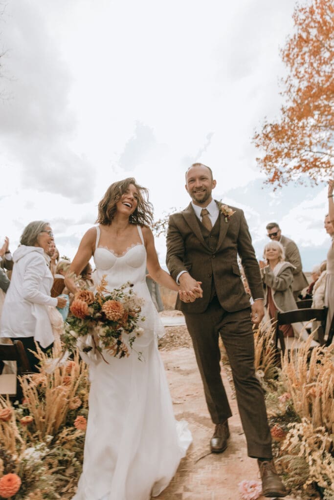 Bride and groom walking down the aisle at their luxury fall Wolf Creek Ranch wedding