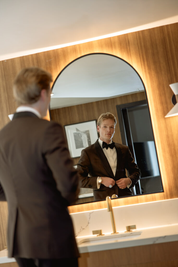 Groom adjusting cufflinks in mid-century modern bathroom mirror, Le Méridien Salt Lake City