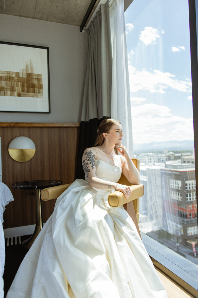 Bride seated by floor-to-ceiling window overlooking downtown Salt Lake City