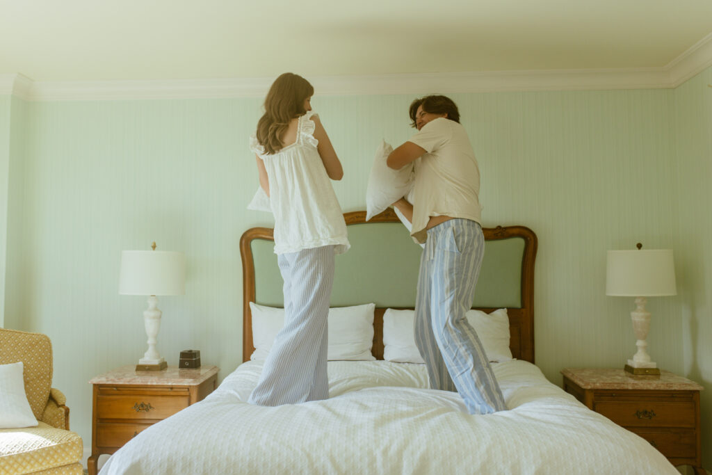 playful pillow fight between newlyweds in pajamas at Grand America Hotel Utah