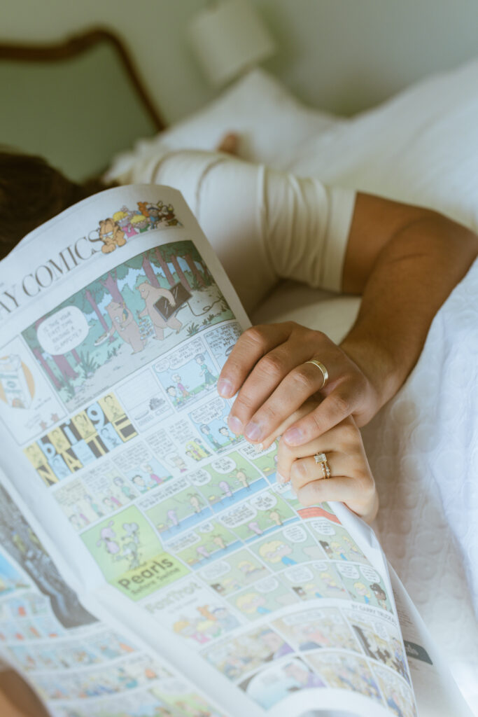Couple reading Sunday comics together in bed, whimsical anniversary session Salt Lake City