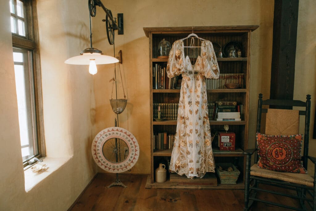 editorial bridal dress hanging from bookshelf 