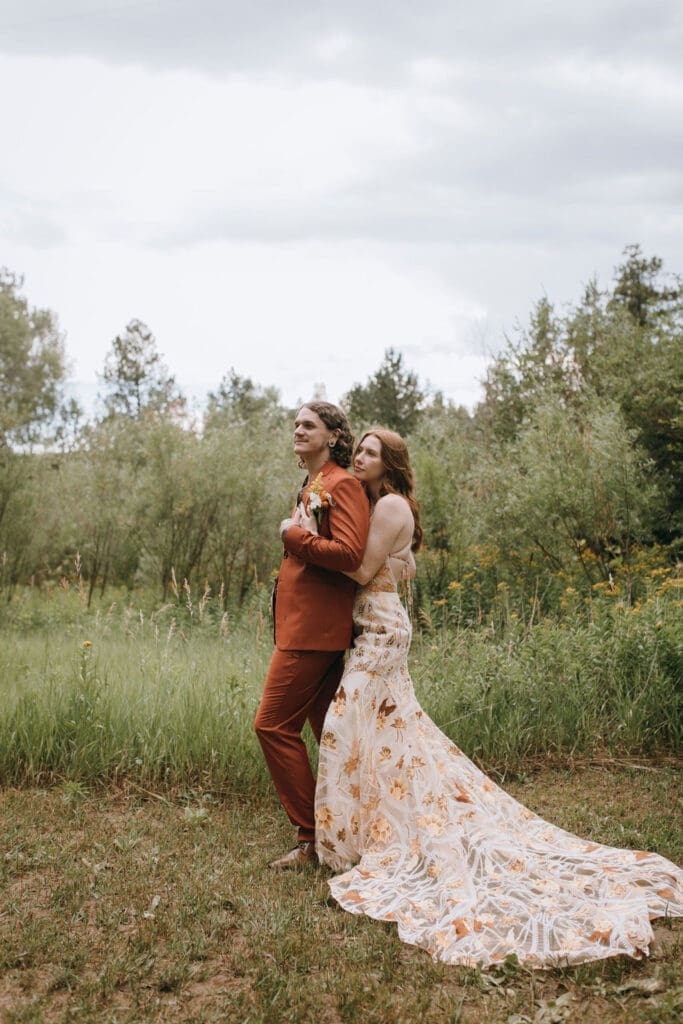 Bride and groom walk hand-in-hand through a wildflower meadow after their intimate Colorado wedding
