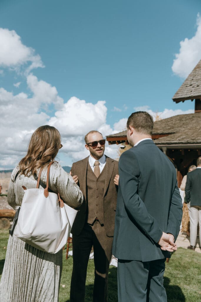 Wedding day cocktail hour groom talking to guests candid